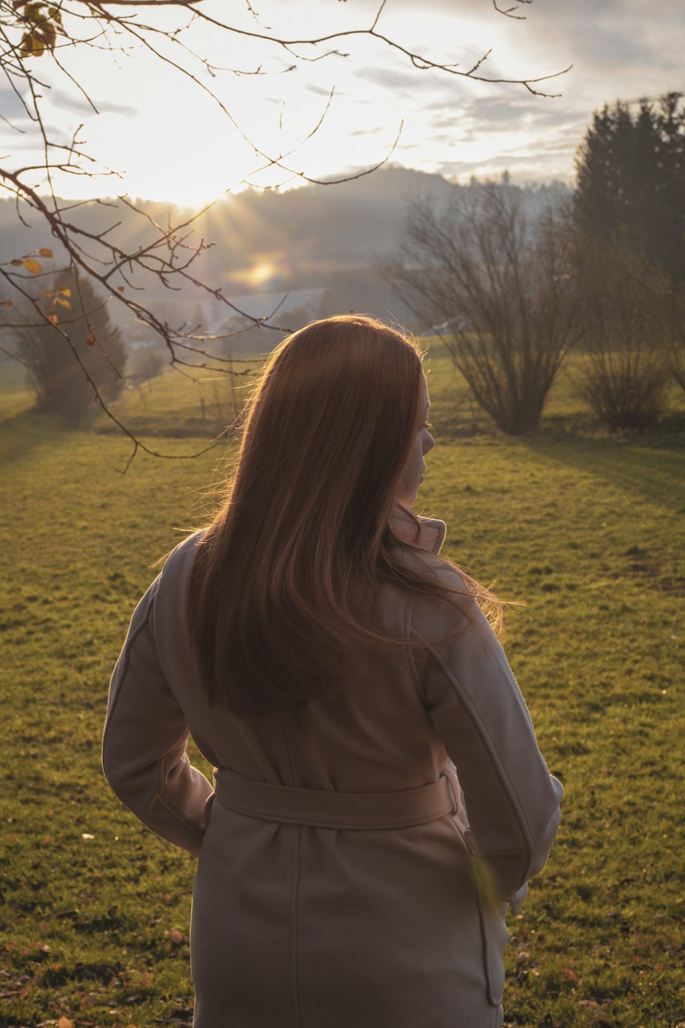 woman in gray jacket standing on green grass field during daytime