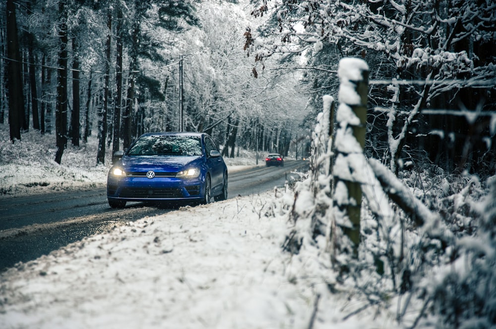 Voiture bleue sur la route enneigée pendant la journée