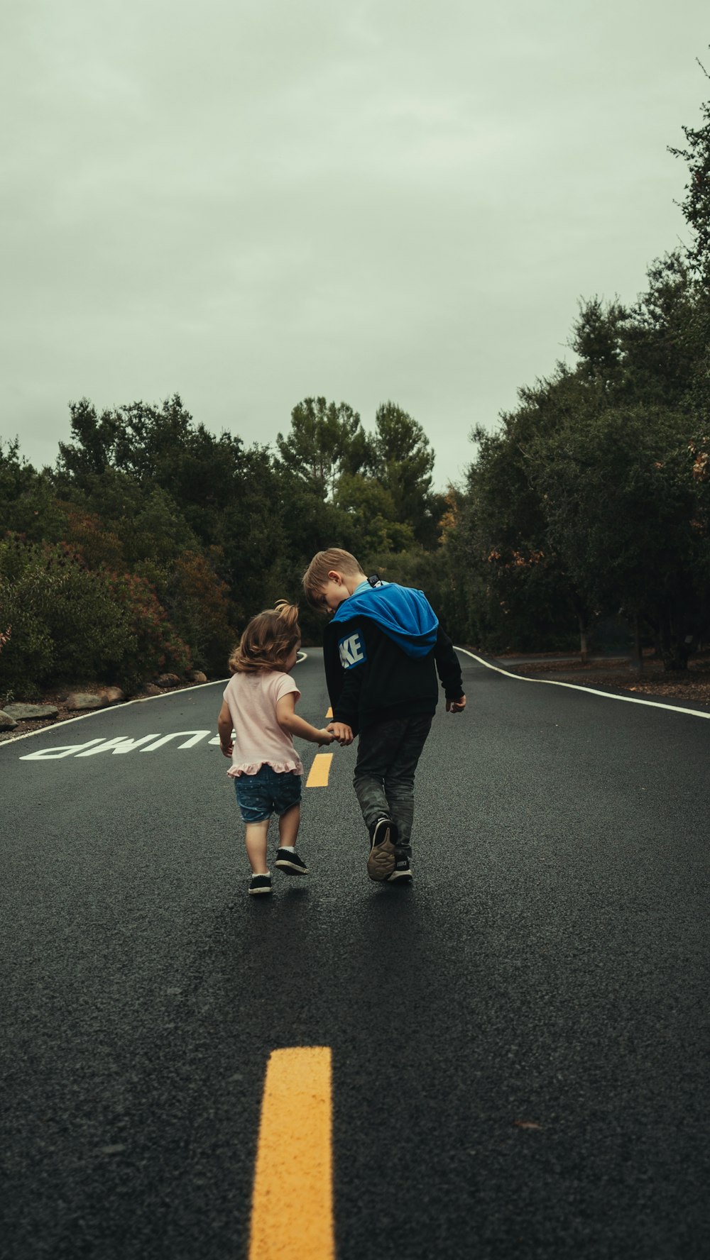 boy in blue t-shirt and blue shorts running on road during daytime