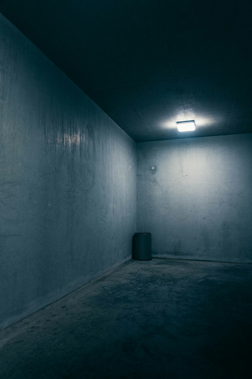 gray concrete wall with black trash bin