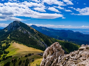 green grass field and mountain under blue sky during daytime