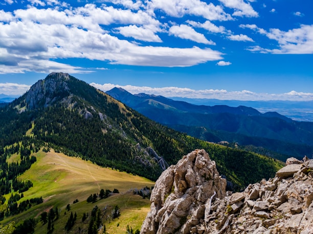 green grass field and mountain under blue sky during daytime