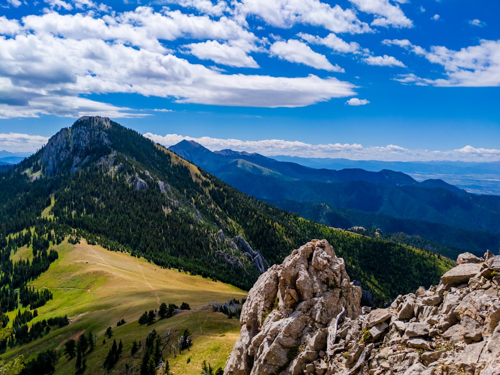 green grass field and mountain under blue sky during daytime