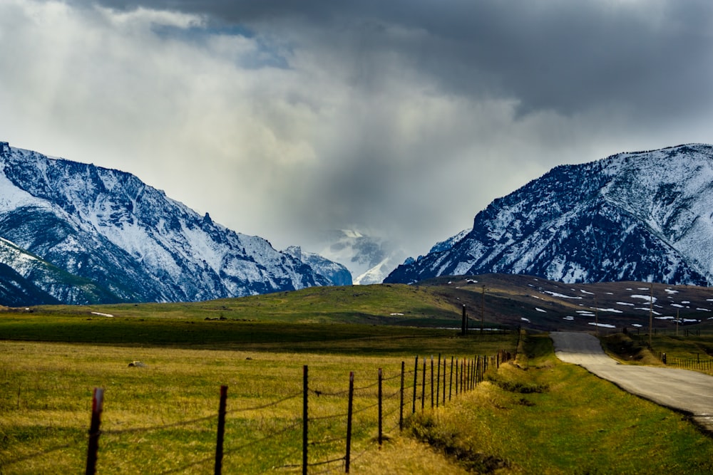 green grass field near mountain under white clouds during daytime