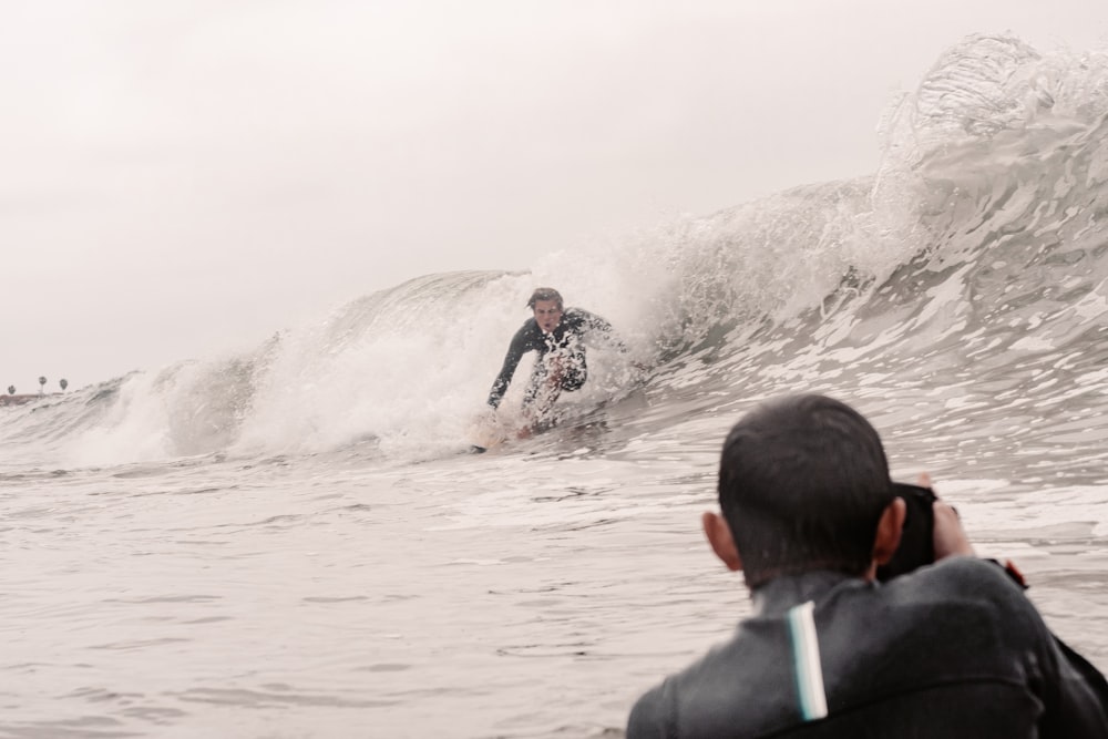 man in black and green jacket surfing on sea waves during daytime