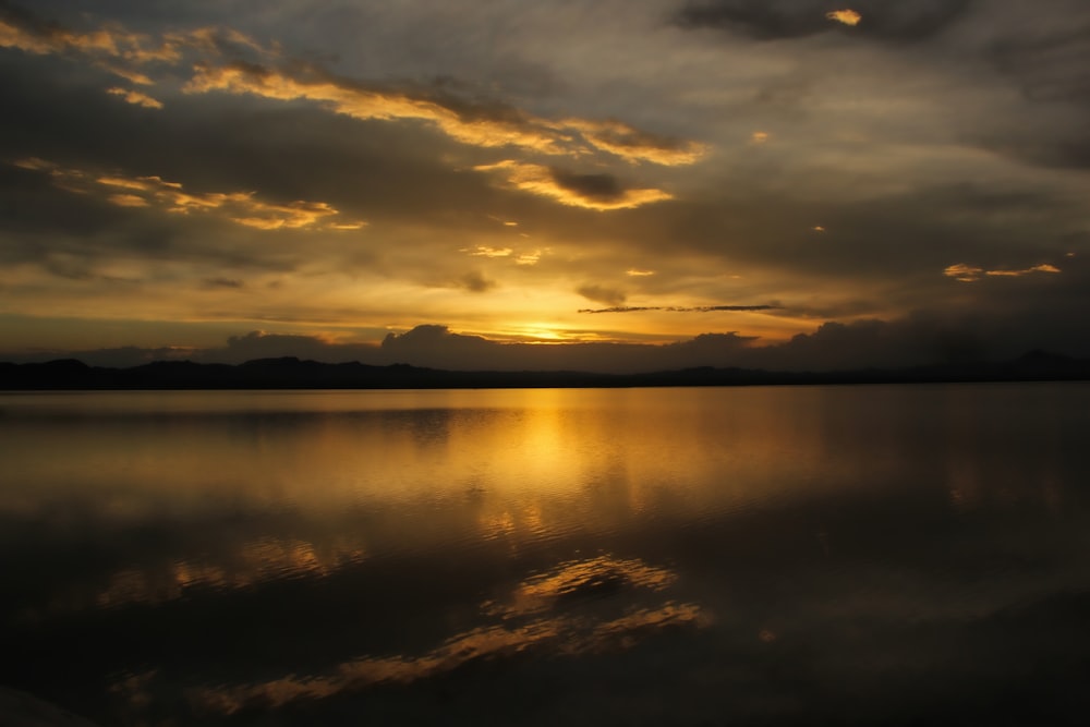 body of water under cloudy sky during sunset