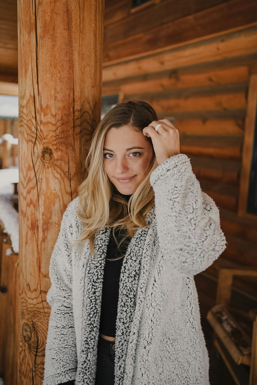 woman in gray coat standing near brown wooden wall