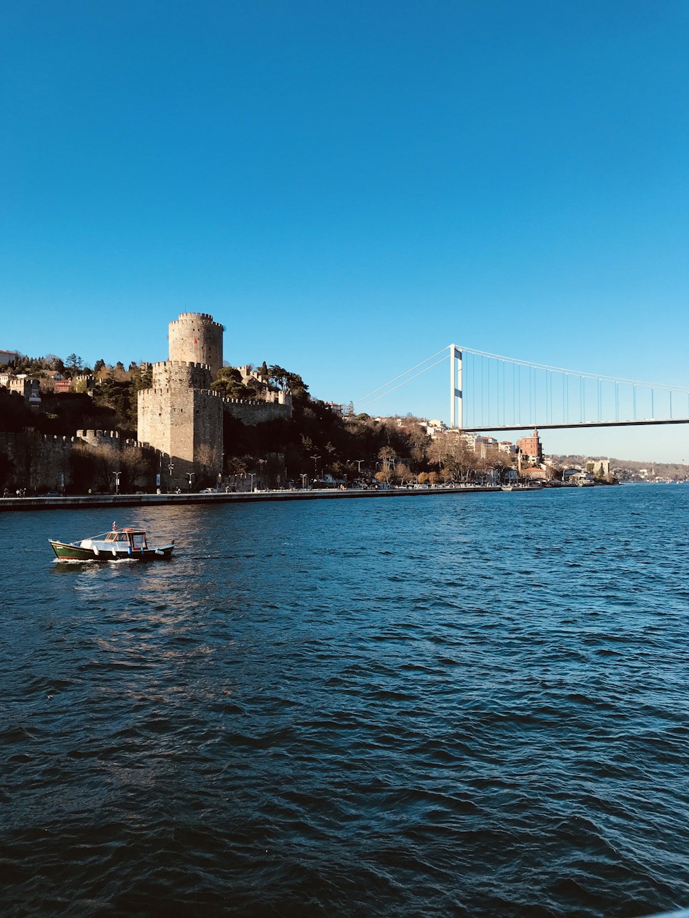 Barco blanco en el mar cerca del puente durante el día