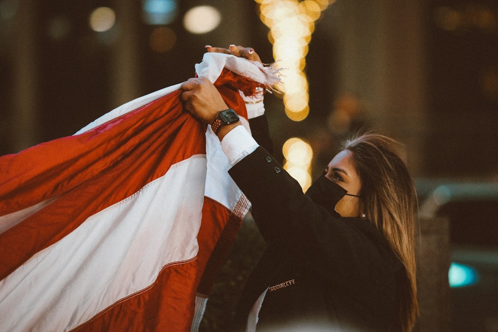 woman in black long sleeve shirt holding red and white striped flag during night time