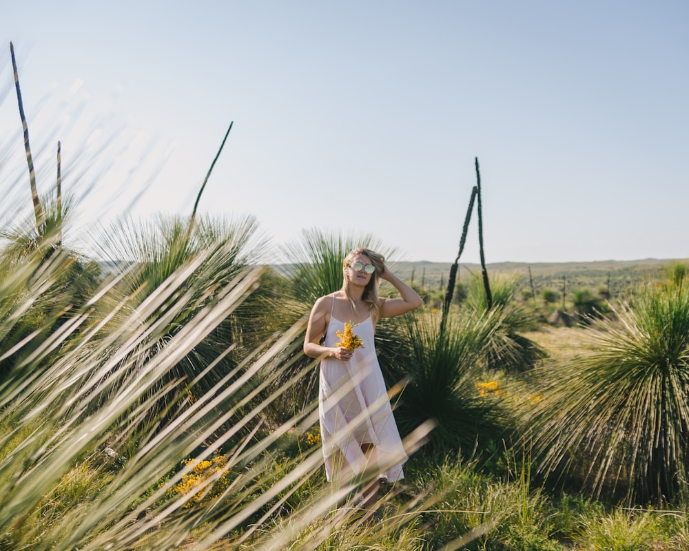 woman in white dress standing on green grass field during daytime