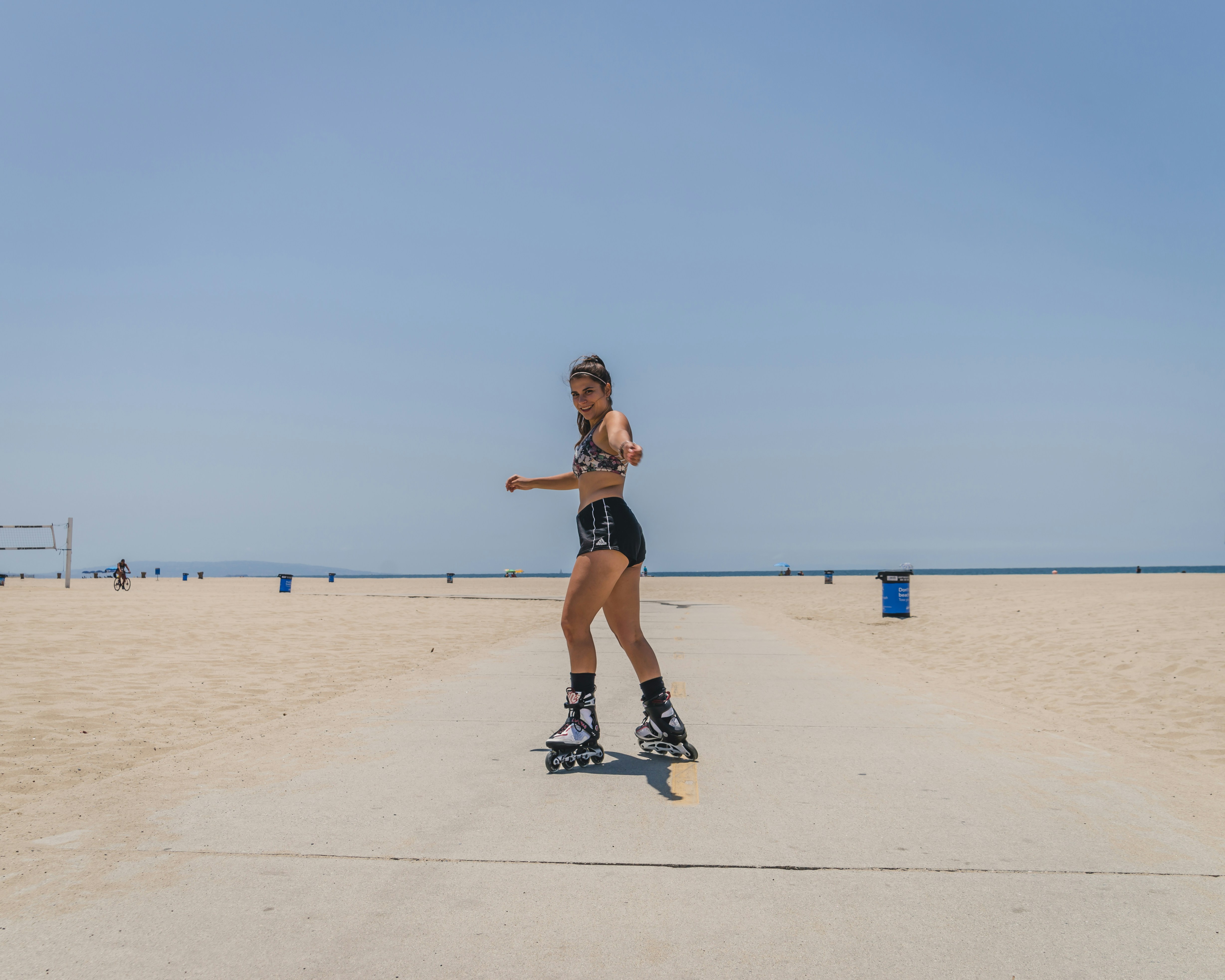Frau in schwarzem Tanktop und schwarzen Shorts, die tagsüber auf weißem Sand laufen