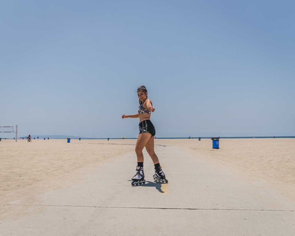 Frau in schwarzem Tanktop und schwarzen Shorts, die tagsüber auf weißem Sand laufen