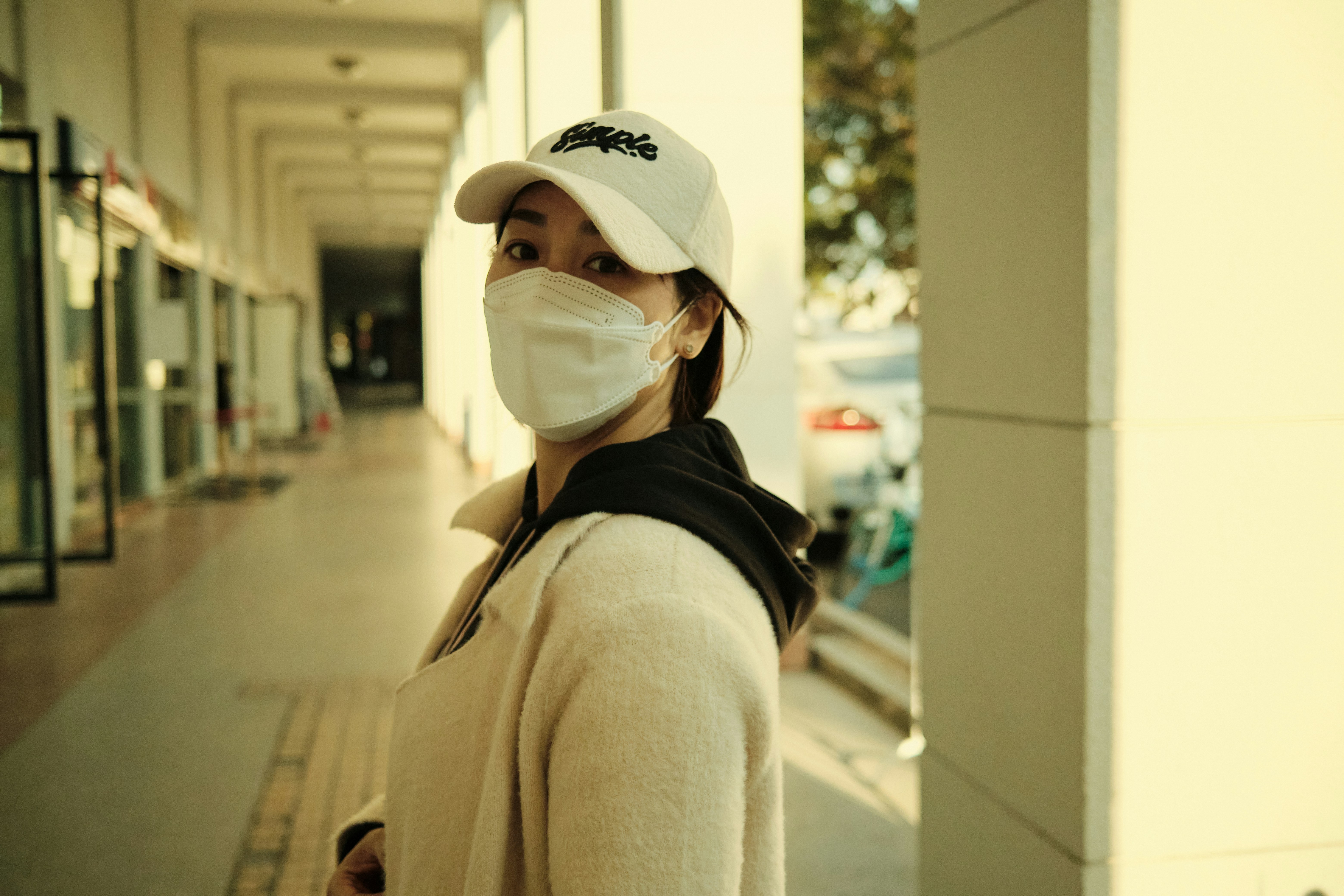 woman in beige coat wearing white cap