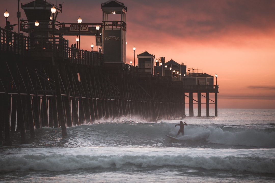 man surfing on sea waves near building during night time
