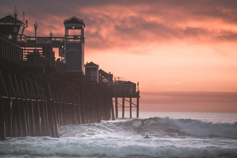 brown wooden house on sea shore during sunset