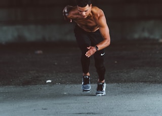 topless man in black pants and black shoes