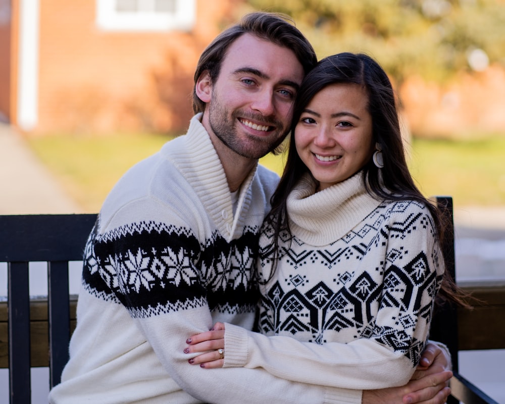 man in white sweater hugging woman in black and white floral scarf