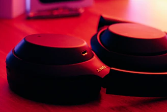 Close-up of sleek wireless headphones resting on a wooden desk with soft natural light.