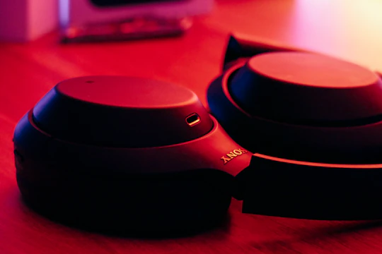 Close-up of golden headphones resting on a sleek black surface with soft ambient lighting.
