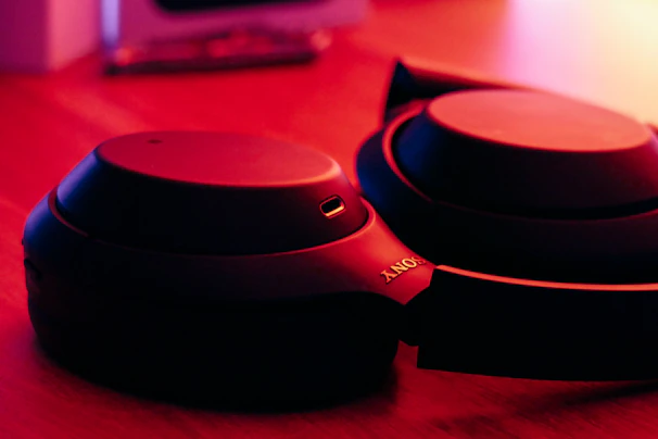Close-up of sleek wireless headphones resting on a wooden desk with soft natural light.