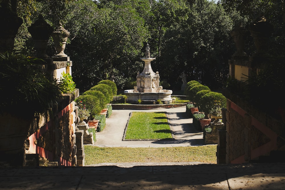 gray concrete fountain in the middle of green trees