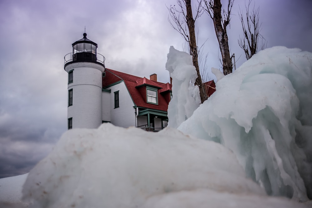 Phare en béton blanc et rouge sous des nuages blancs pendant la journée