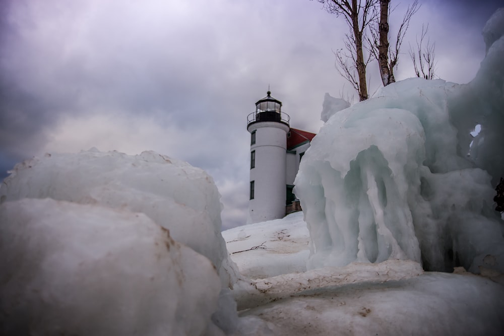 white and black lighthouse covered by snow during daytime