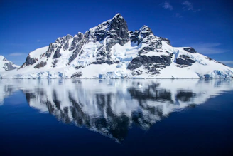 snow covered mountain near body of water during daytime