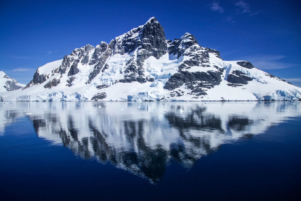 snow covered mountain near body of water during daytime