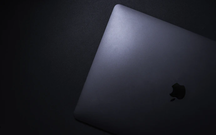 Overhead shot of a laptop on a sleek black surface with turquoise and orange highlights.