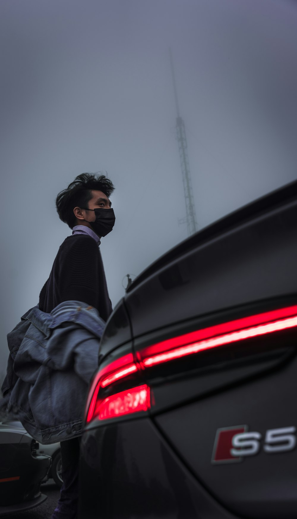 man in black jacket and black knit cap standing beside car