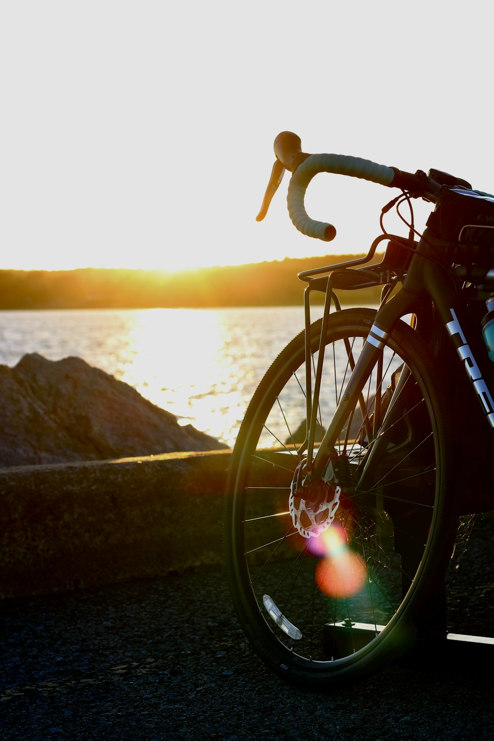 black bicycle near body of water during sunset