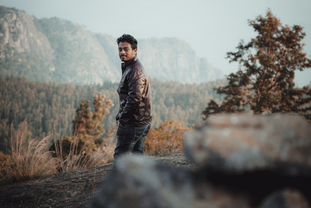 man in brown jacket standing on brown grass field during daytime