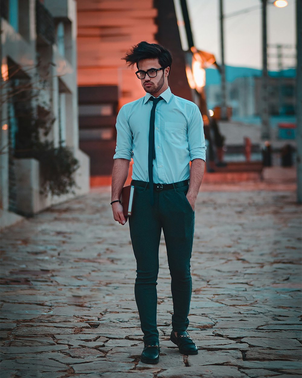 man in white dress shirt and black pants wearing black sunglasses standing on sidewalk during daytime