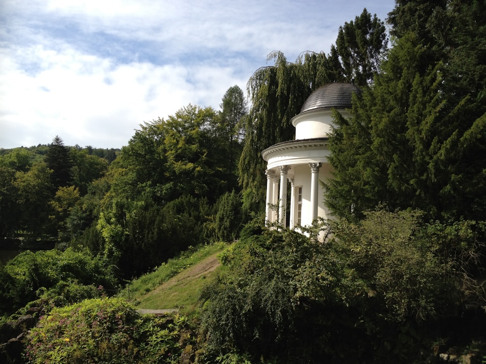 Weißes Betongebäude auf grünem Rasenfeld unter weißen Wolken und blauem Himmel tagsüber