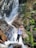 woman in black tank top and black pants standing on rock near waterfalls during daytime