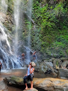 A group of happy tourists exploring a lush waterfall in Samana surrounded by green foliage.