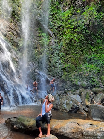 A group of happy tourists exploring a lush waterfall in Samana surrounded by green foliage.