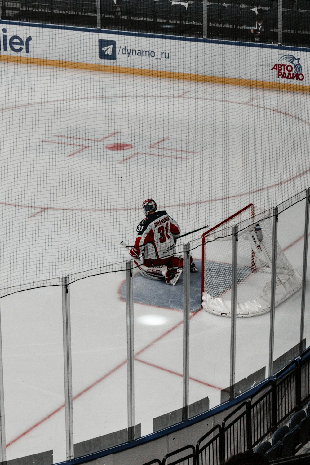 man in black and red jacket riding on ice hockey field