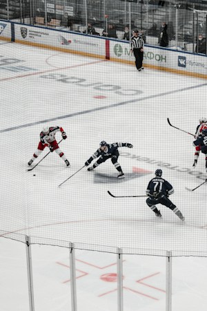 Ice hockey players battling for the puck during a game, similar to the Golden Knights and Utah Mammoth preseason matchup at T-Mobile Arena