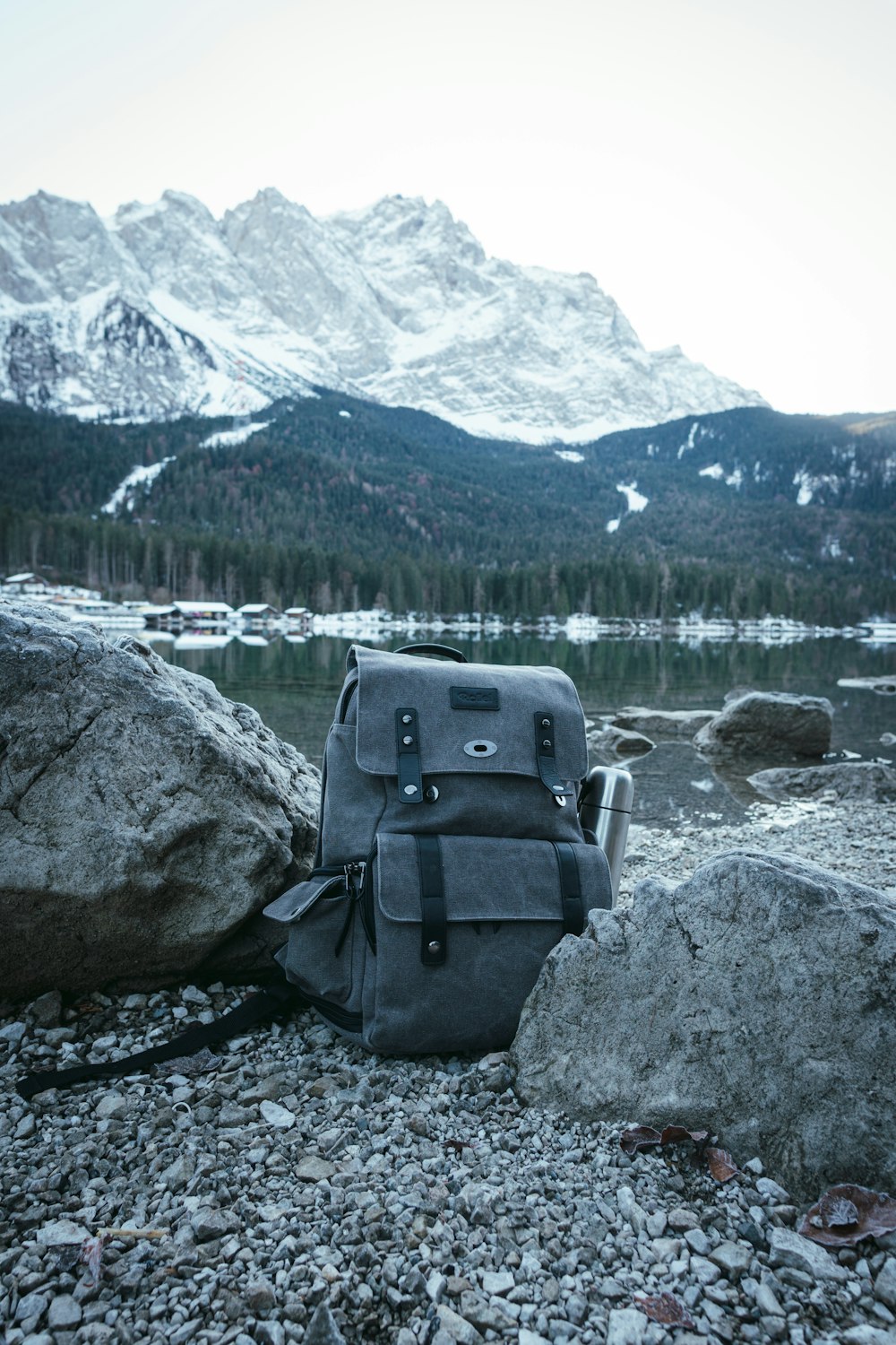 sac à dos bleu et gris sur roche grise près du plan d’eau pendant la journée