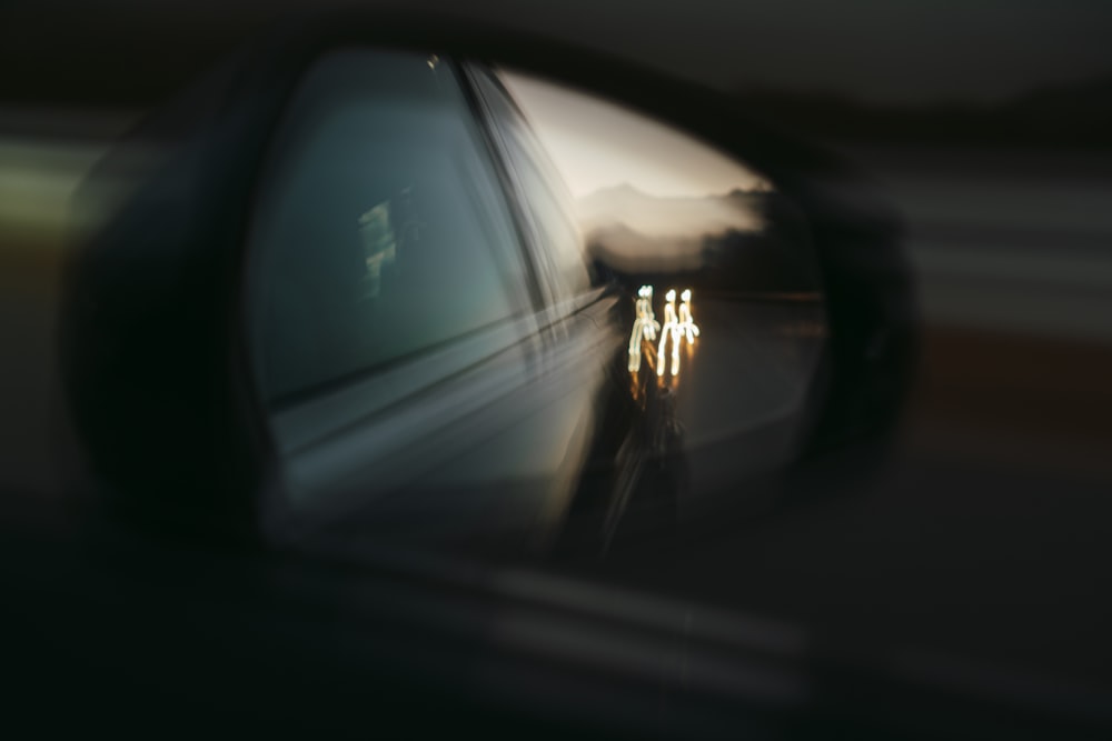 person in black jacket standing in front of car side mirror