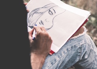 person in blue denim jeans holding white printer paper