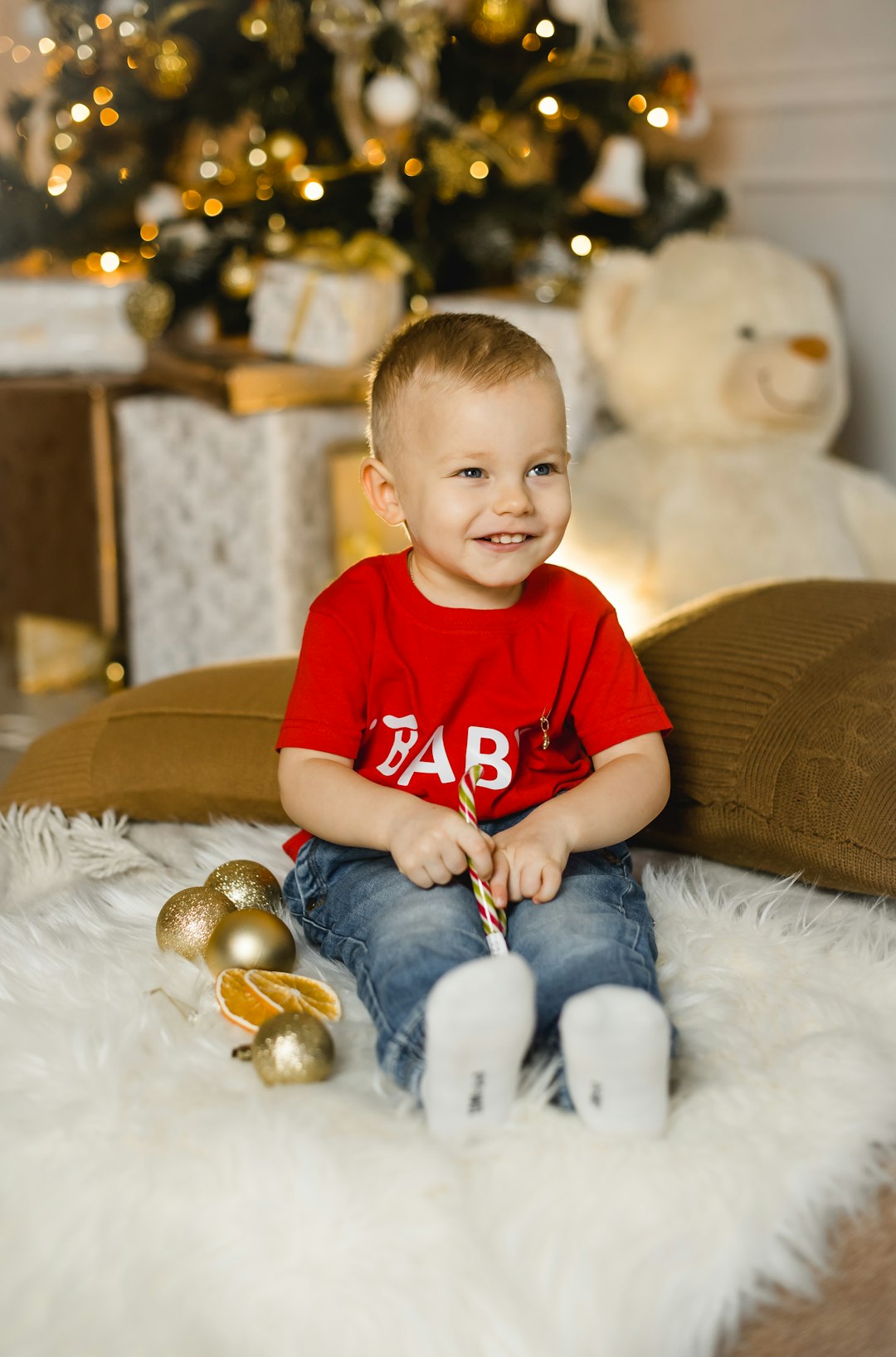 boy in red crew neck t-shirt and blue denim jeans sitting on white fur textile