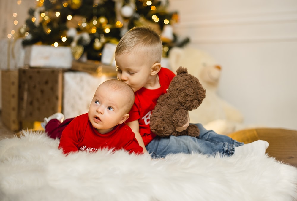 boy in red long sleeve shirt sitting on white fur textile