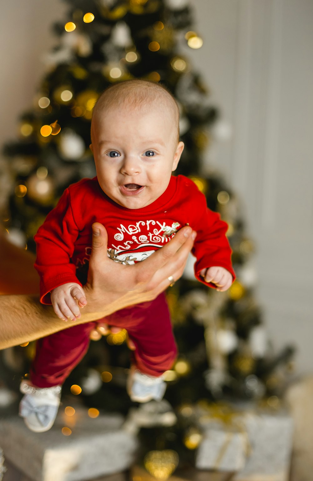 baby in red onesie sitting on brown wooden table