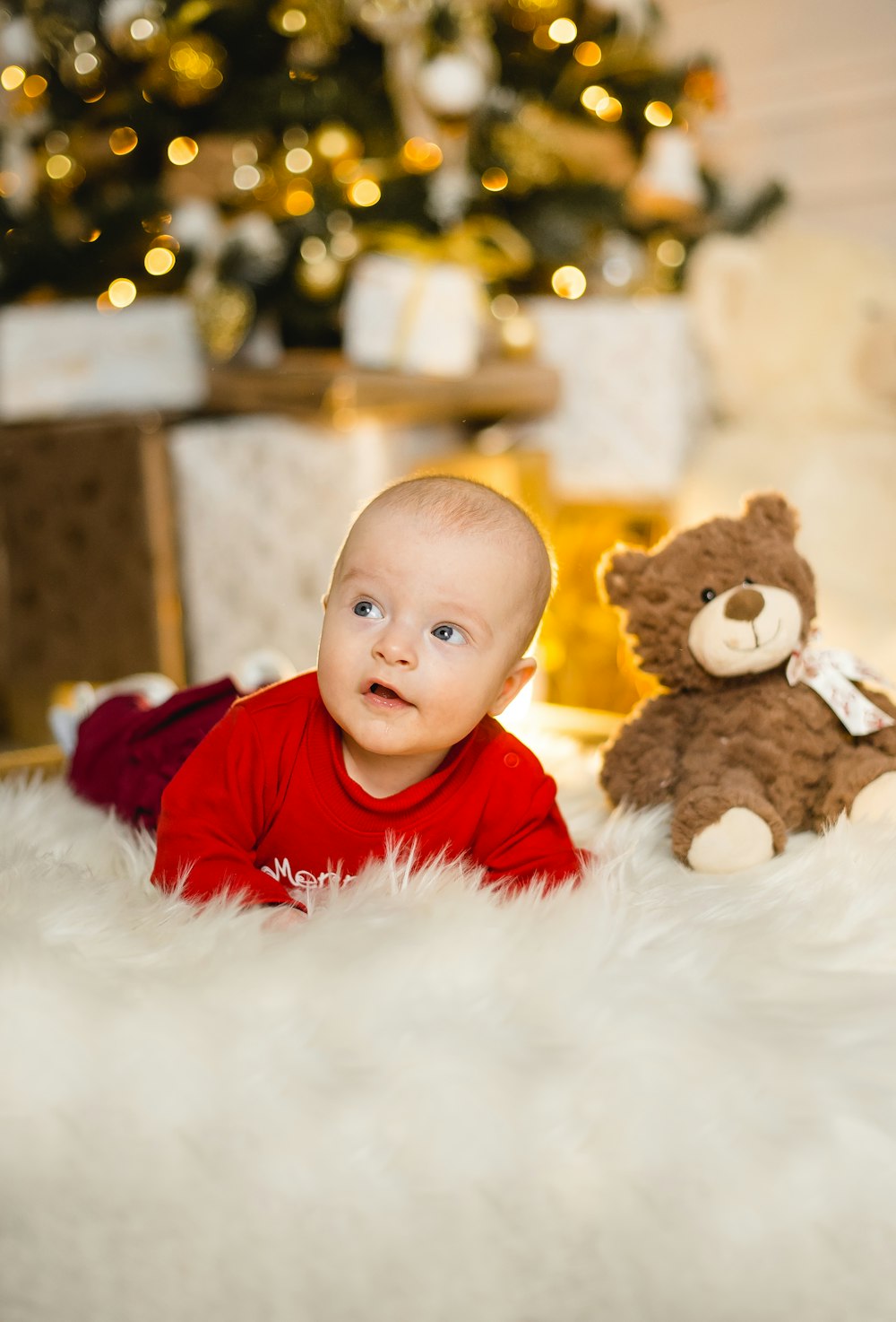 boy in red shirt holding brown bear plush toy