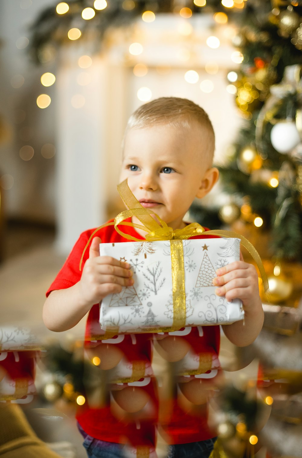 boy in red polo shirt holding white and brown gift box
