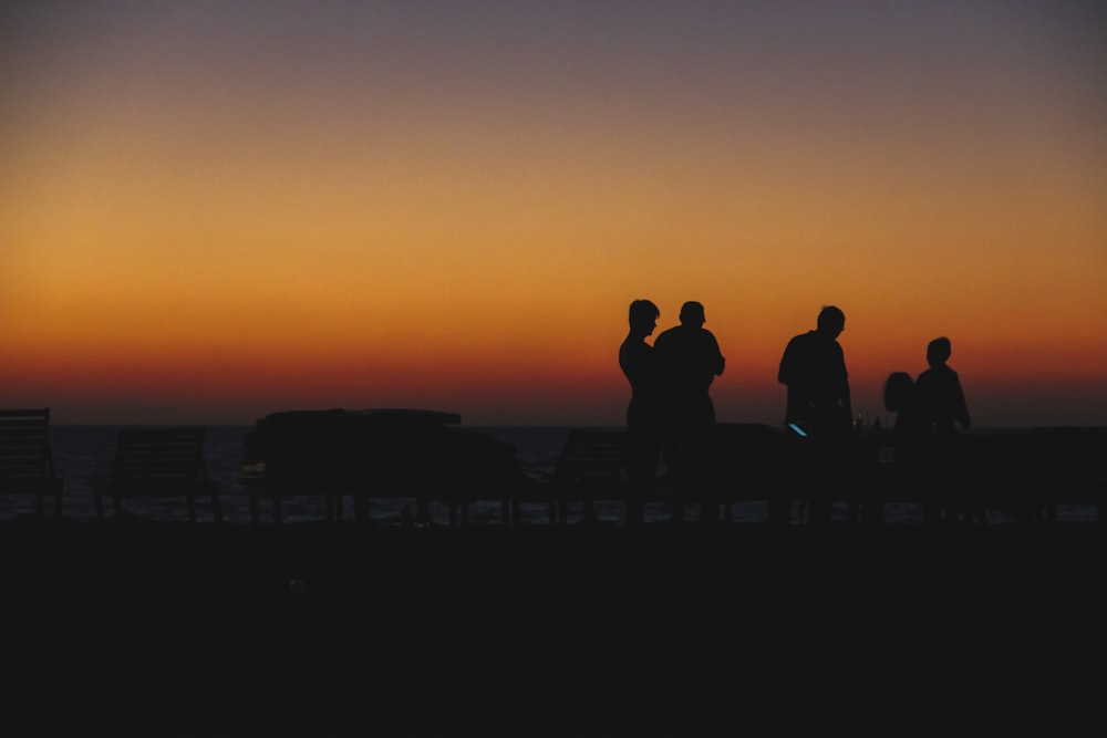 silhouette of people standing on roof during sunset