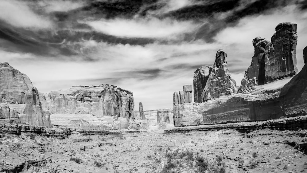 grayscale photo of rock formation under cloudy sky